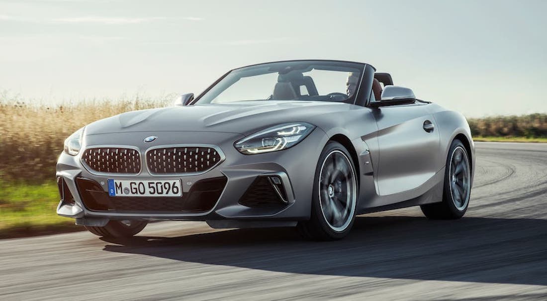 A silver 2021 BMW Z4 is driving past a field.