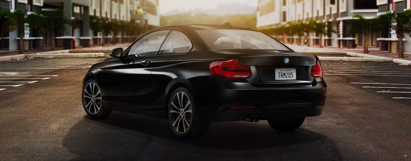 A black 2019 BMW 2 Series coupe is parked in the middle of a parking lot.