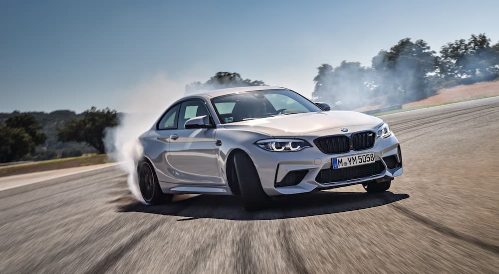 A white 2021 BMW M2 Competition is shown drifting around a corner.