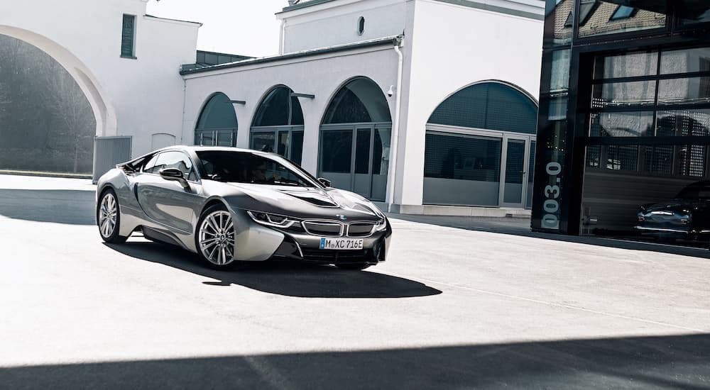 A silver 2020 BMW i8 is shown driving through a city.