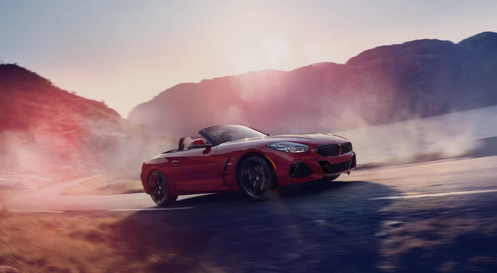 A red 2022 BMW Z4 M40i is shown driving on a dirt road after researching BMW lease deals.