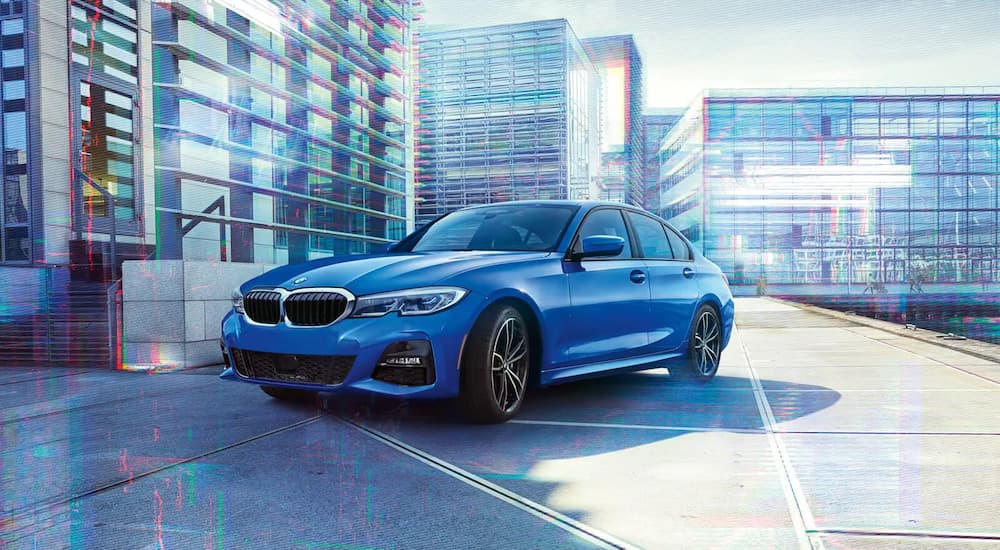 A blue 2022 BMW Series 3 Sport is shown driving on a city street.