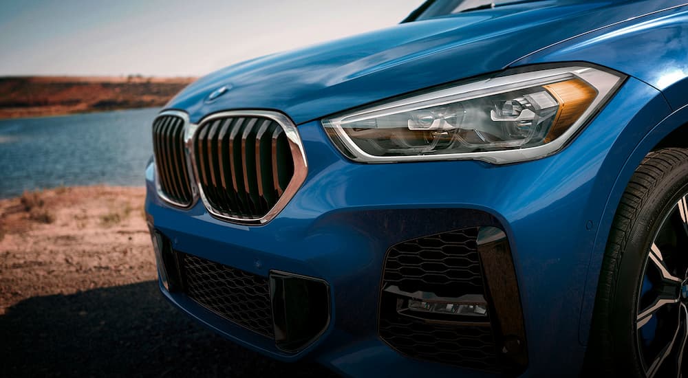A close up shows the grille and headlights of a blue 2022 BMW X1.