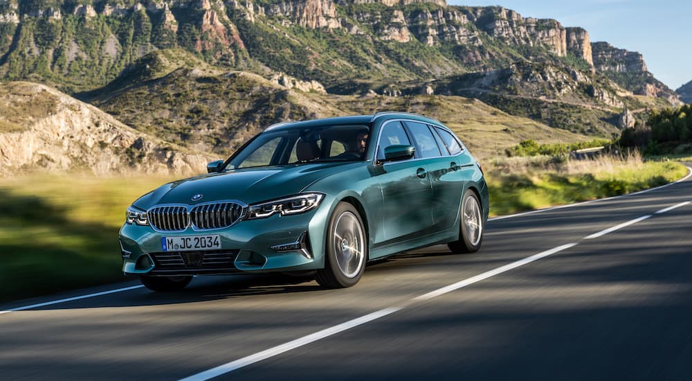 A green 2022 BMW 3 Series is shown driving on an open road.