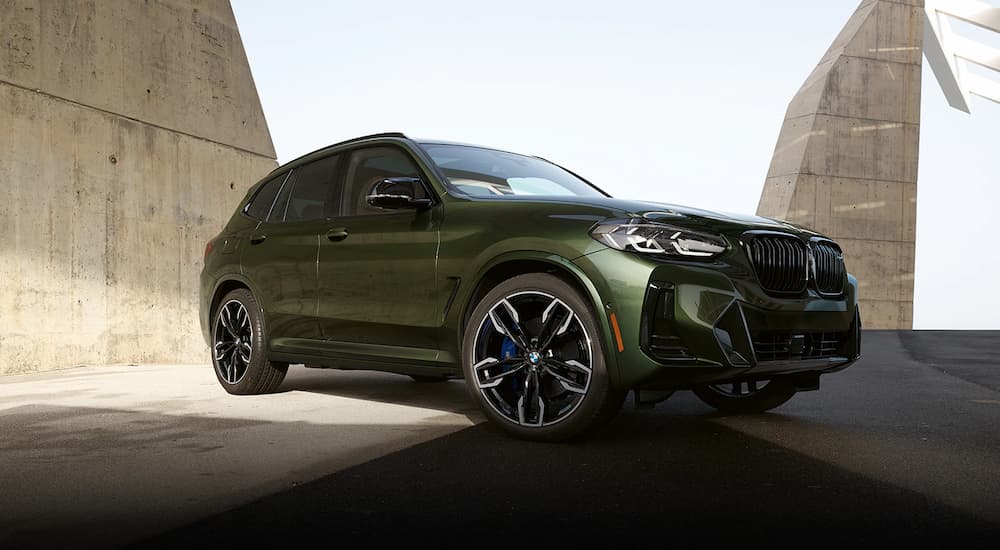 A green 2022 BMW X3 M40i is shown parked near a concrete wall.