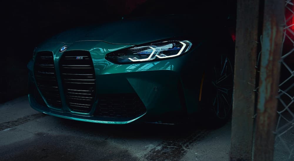 The front of a green 2022 BMW M3 is shown while parked in a garage.