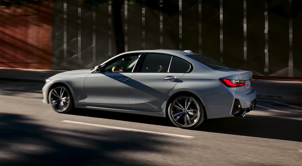 A grey 2020 BMW 3 Series is shown from the side driving on a city street.