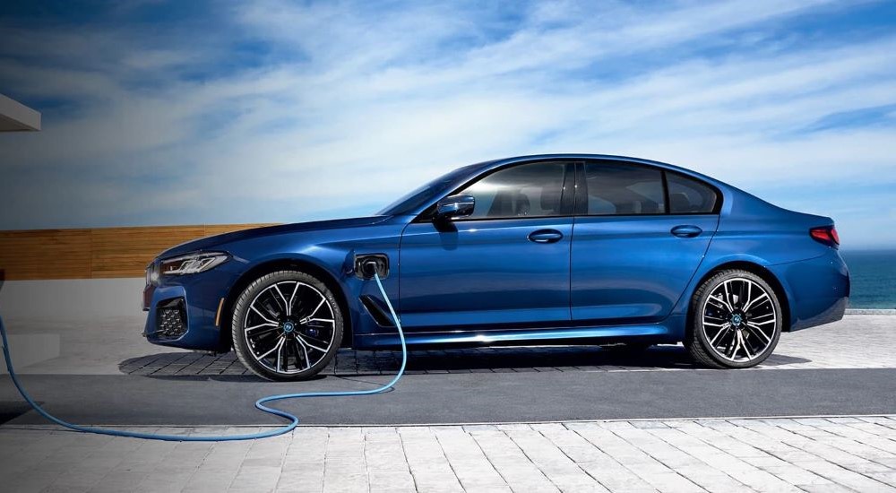 A blue 2023 BMW 530e is shown from the side charging.