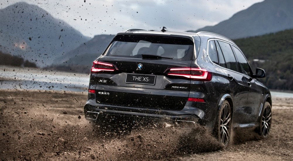 A black 2023 BMW X5 is shown shown from the rear kicking up dirt.