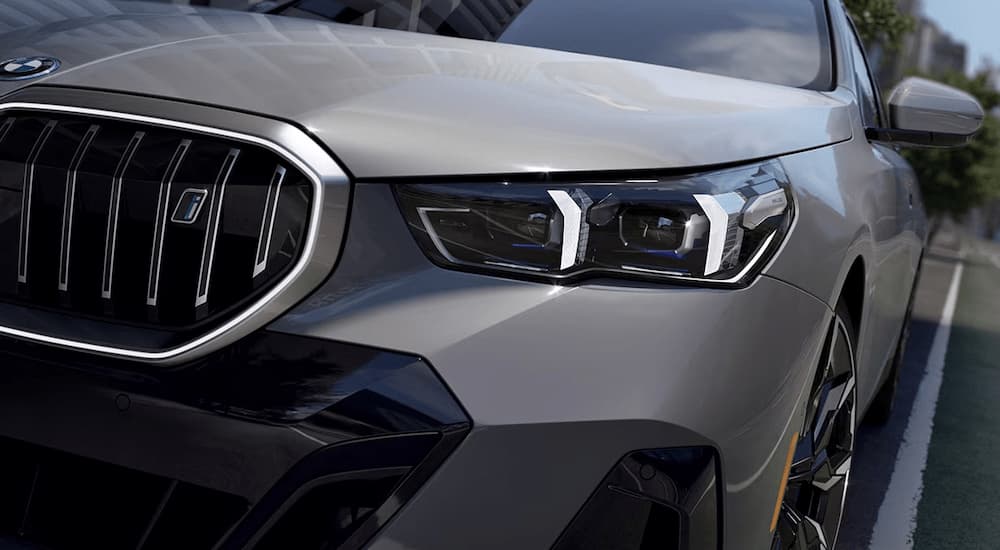 A close up of the headlight on a grey 2023 BMW i5 is shown at a BMW store.